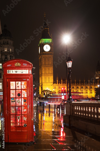 Popular tourist Big Ben and Houses of Parliament with red phone booth in night lights illumination in London  England  United Kingdom