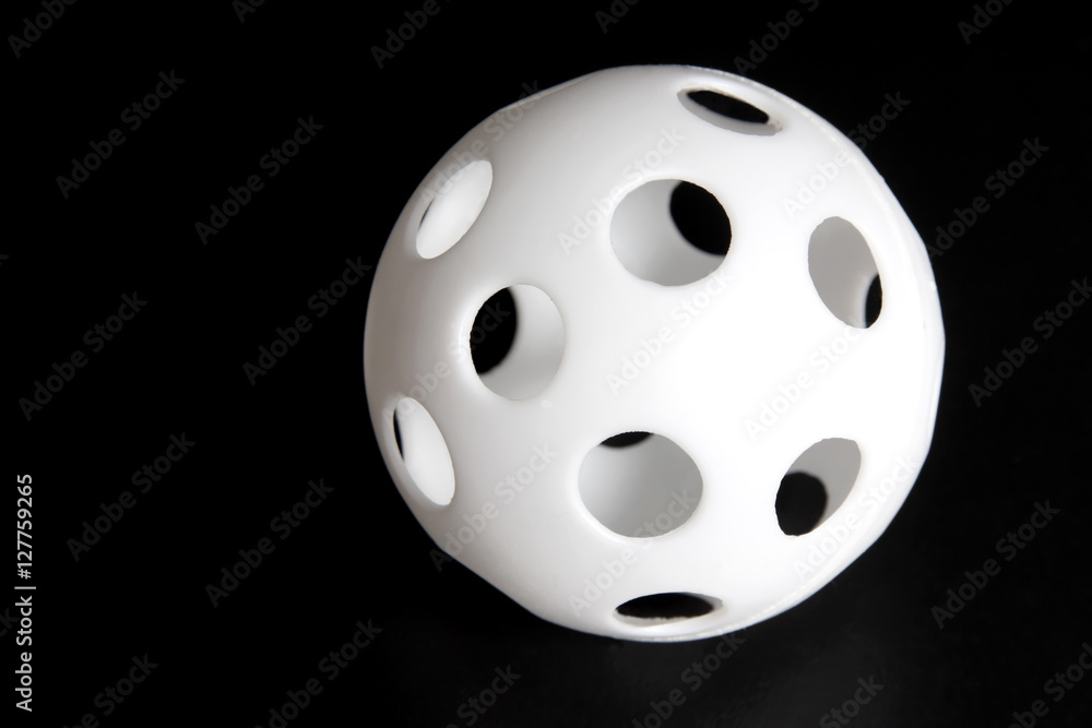 Cheap Whiffle Ball-type knock-off plastic ball with holes. Horizontal. 