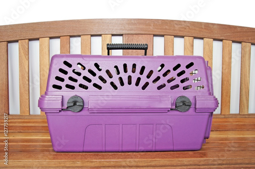 Cat inside cat carrier awaiting his appointment on bench at veterinarian. Horizontal.