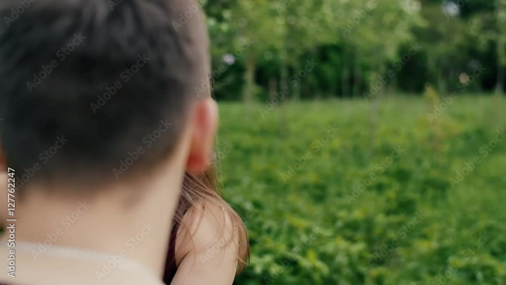 Womans hand touches leaves. Beautiful young woman walks in front of her man, turns head Backview slow mo, steadicam shot Womans hand touches leaves. Beautiful young woman walks in front of her man, turns head Backview slow mo, steadicam shot