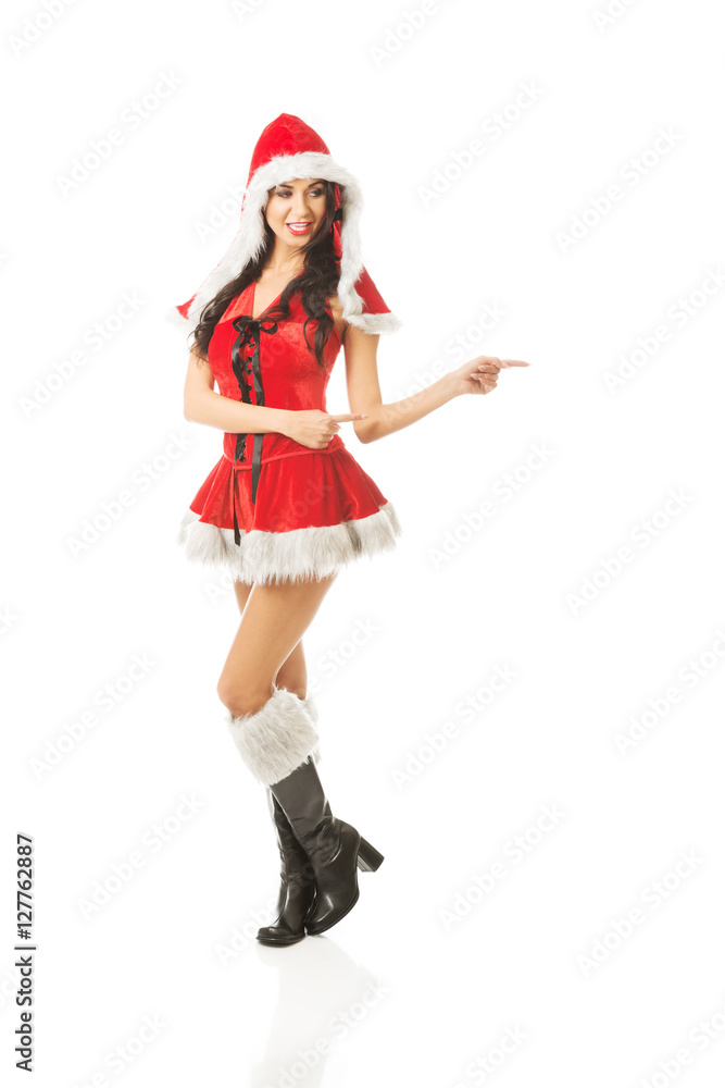 Beautiful slim woman wearing santa clothes and pointing to the right Beautiful slim woman wearing santa clothes and pointing to the right