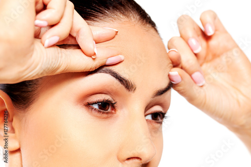 Worried young woman checking wrinkles on forehead