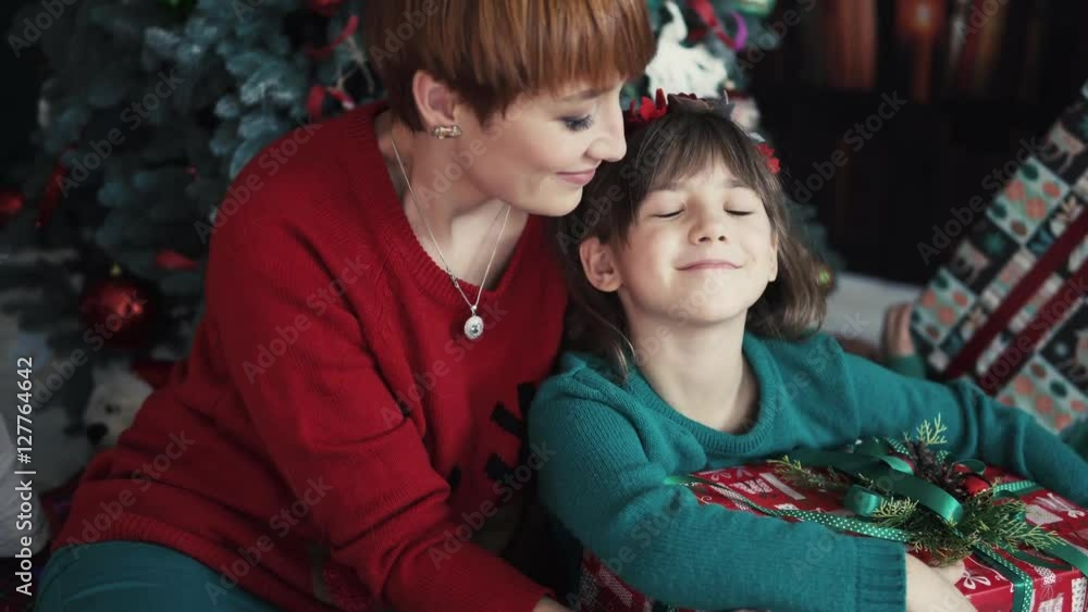 Happy mother having fun with her kid daughter and gift box before christmas tree Happy mother having fun with her kid daughter and gift box before christmas tree