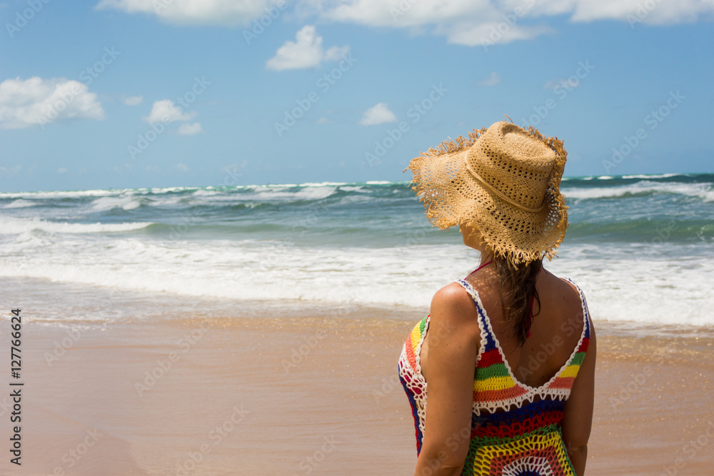 Foto de mujer en la playa, vestido de hilo y sombrero de mimbre do Stock