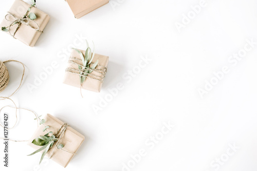 creative arrangement pattern of craft boxes and green branches on white background. flat lay  top view