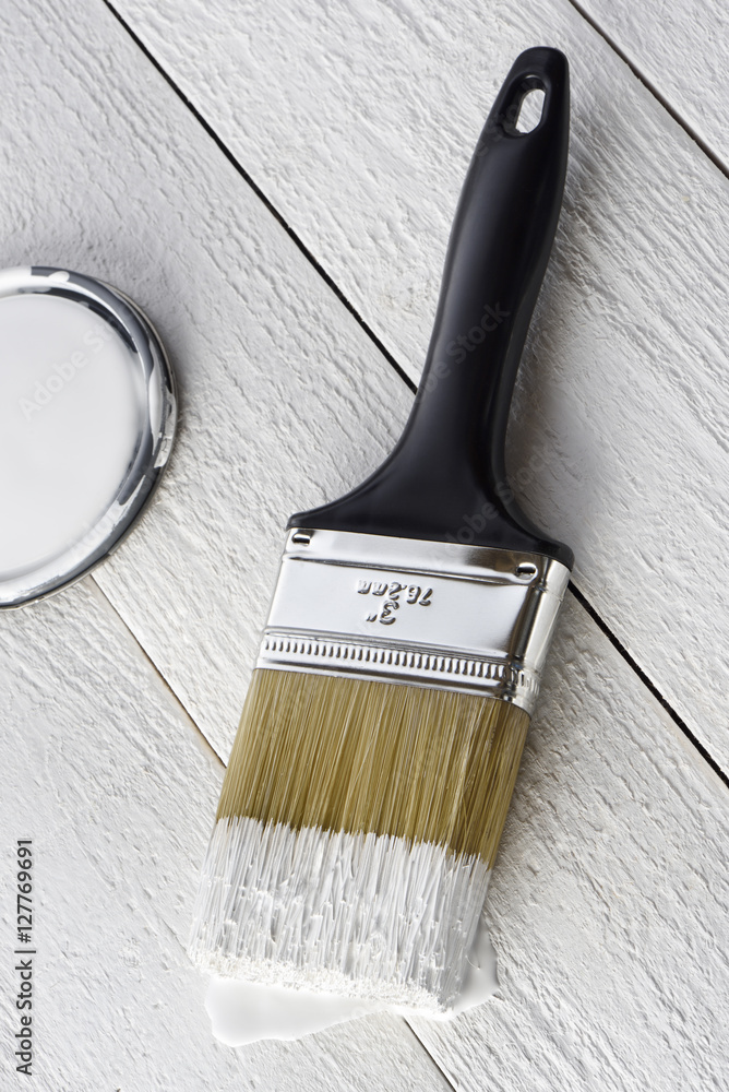 Paintbrush with white paint and can cover on a white background Stock