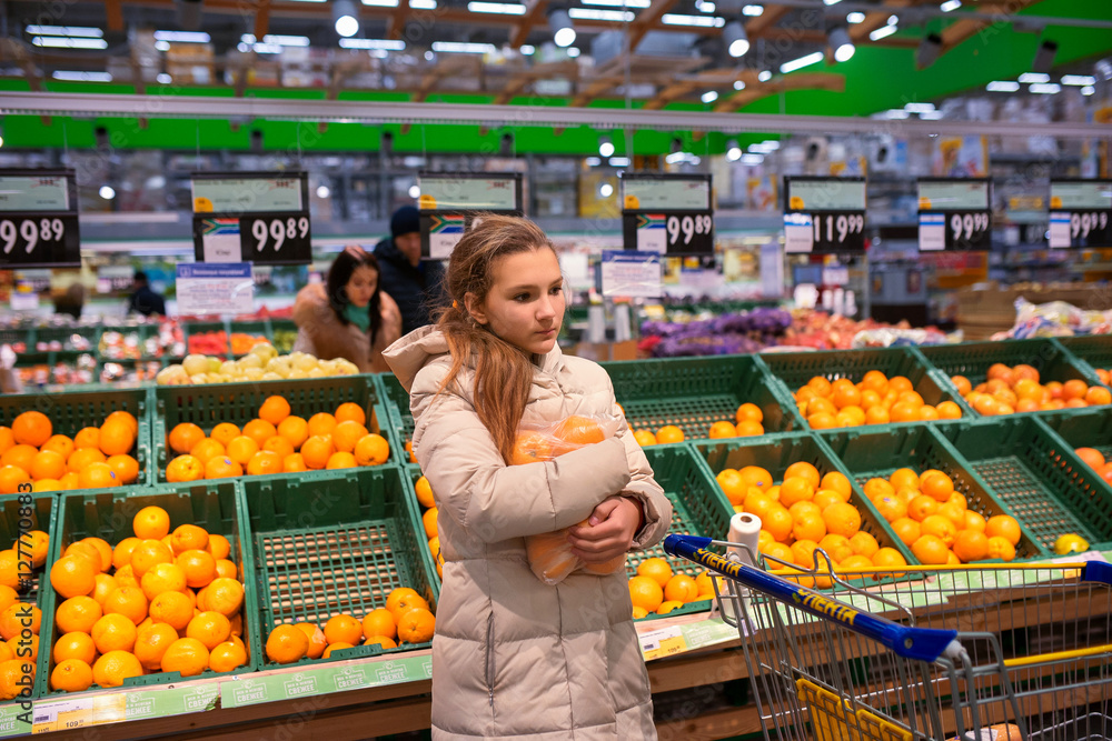 Девочка в супермаркете возле стеллажей с апельсинами