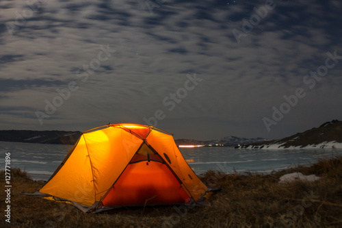 Yellow tent at night on the shore of lake Baikal in winter