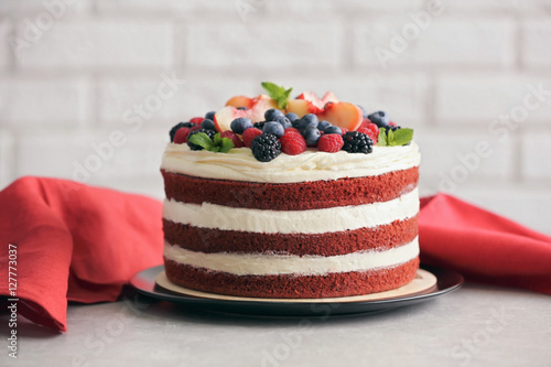 Delicious cake with fruit and berries decoration on gray table