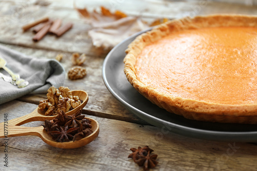 Plate with delicious pumpkin cake and ingredients in wooden spoons, closeup