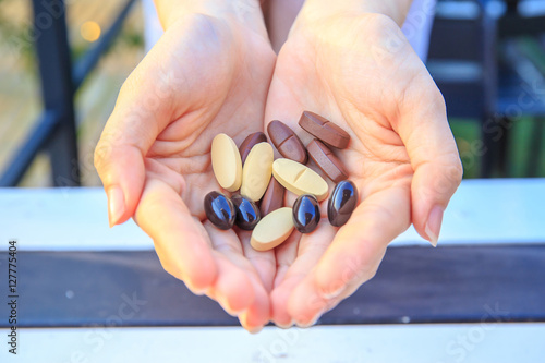 Closeup to multivitamin tablets on two hand of pretty women or girl.