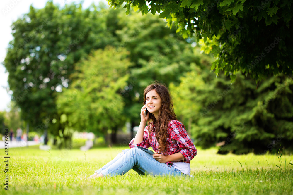Young beautiful woman talking on the phone and holding a touchpad outdoors. Young beautiful woman talking on the phone and holding a touchpad outdoors.