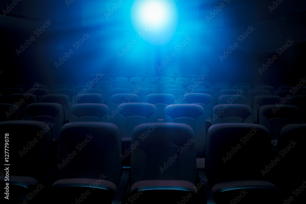 Fototapeta premium Dark film theater with projection light and empty seats