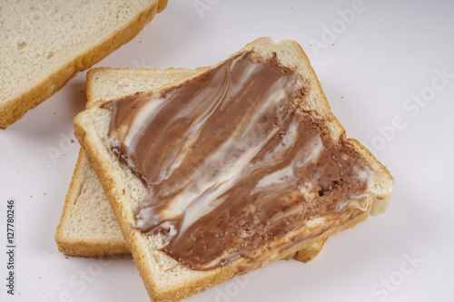Slice of bread with chocolate hazelnut spread isolated on white
