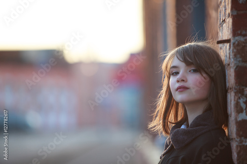 Portrait of pretty teenager girl on wall bricks background  

