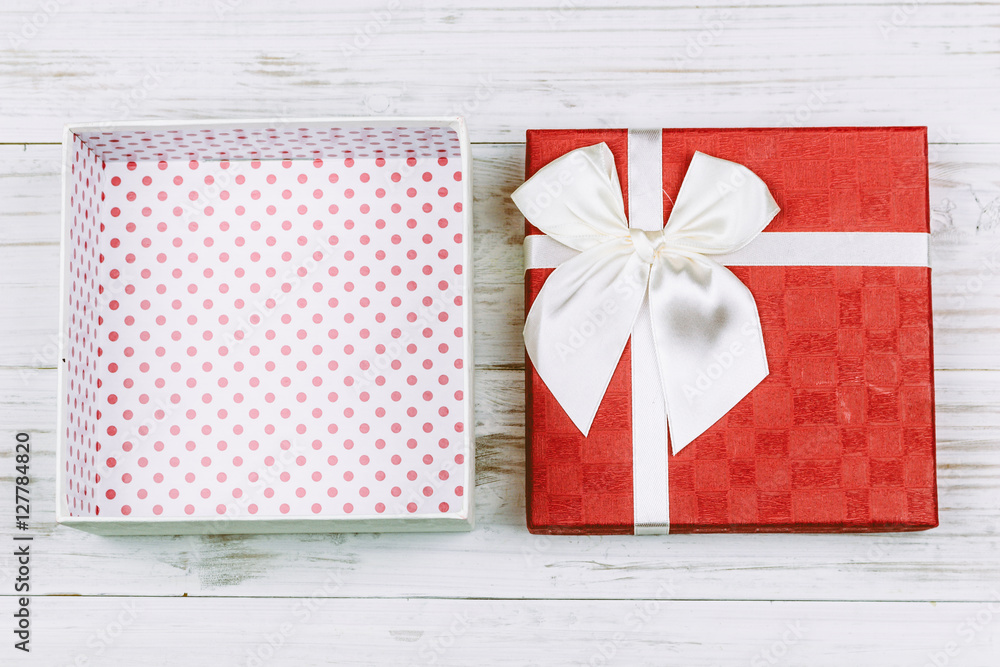 Fototapeta premium Red gift box with ribbon on wooden background
