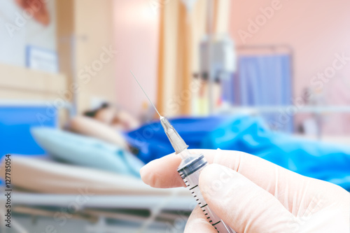 Medical syringe in the doctor's hands on the patient's in room h photo
