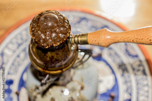 Brewing fresh Turkish coffee pot on portable stove.