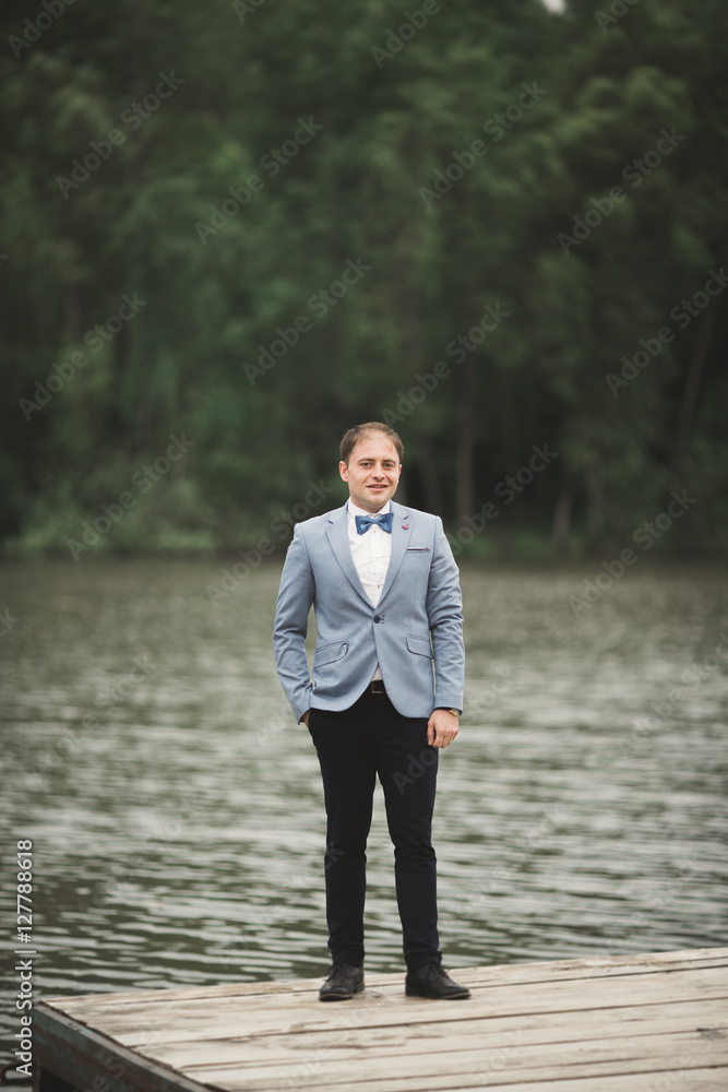 Man, groom posing near forest and lake Man, groom posing near forest and lake