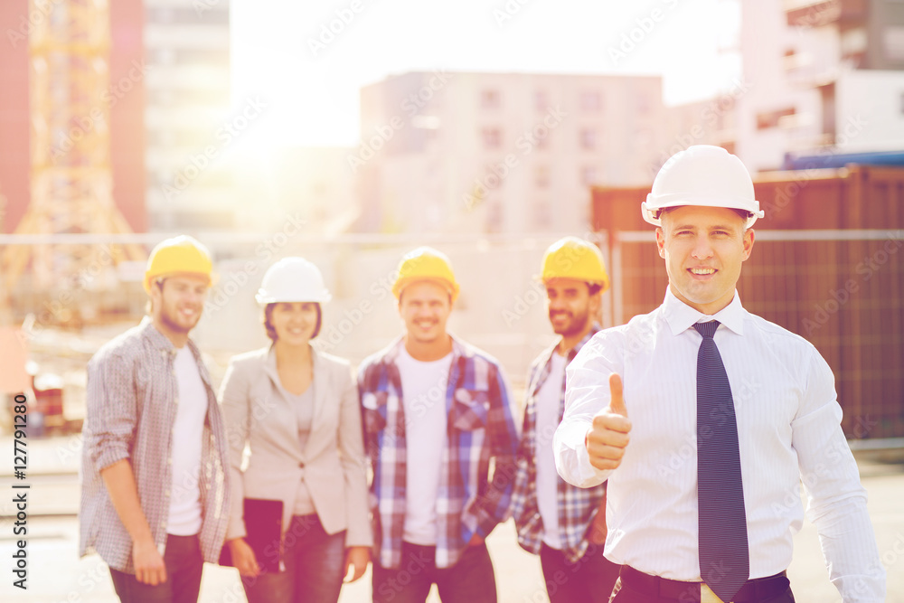 group of smiling builders in hardhats outdoors group of smiling builders in hardhats outdoors