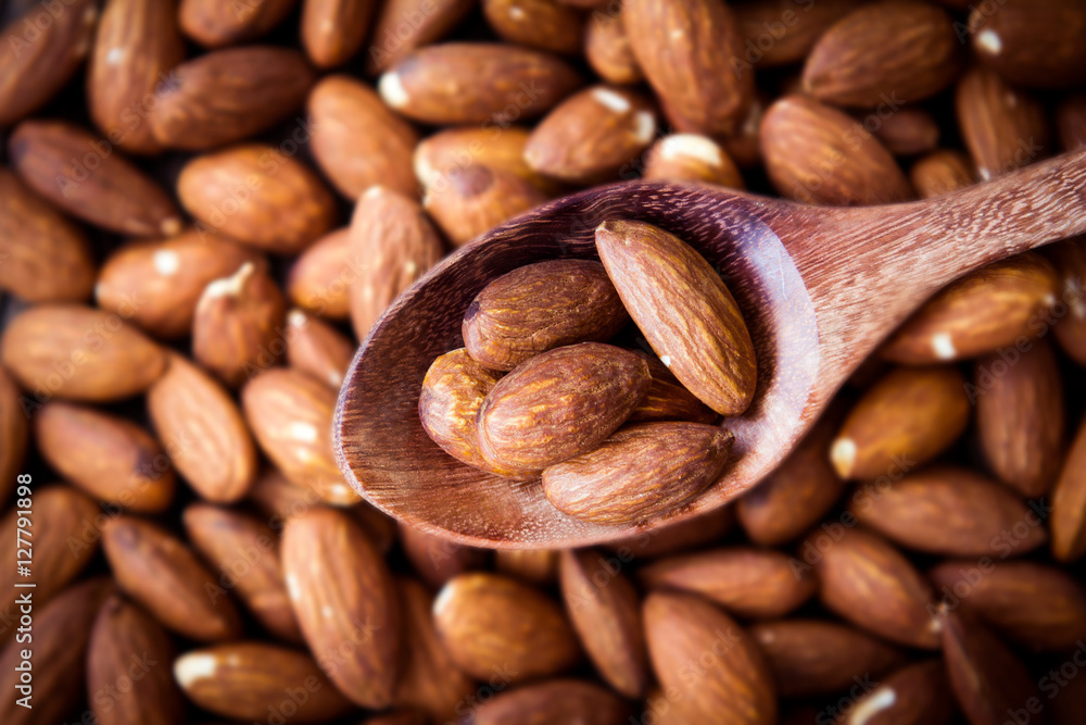 close up Peeled almonds nut in spoon on almond background close up Peeled almonds nut in spoon on almond background