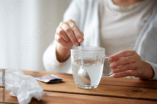 woman stirring medication in cup with spoon