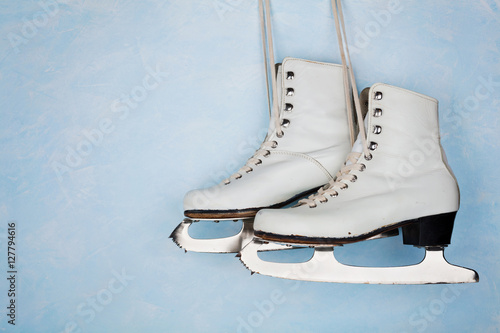 Vintage ice skates for figure skating hanging on the background of blue rustic wall.