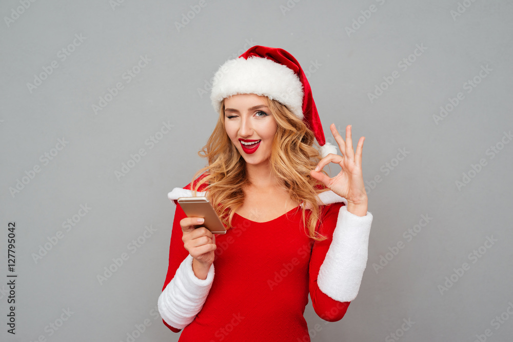 Woman in santa costume using cell phone and showing ok Woman in santa costume using cell phone and showing ok