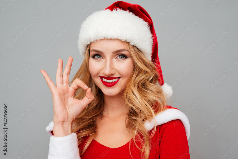 Cheerful woman in santa costume and hat showing ok sign Cheerful woman in santa costume and hat showing ok sign