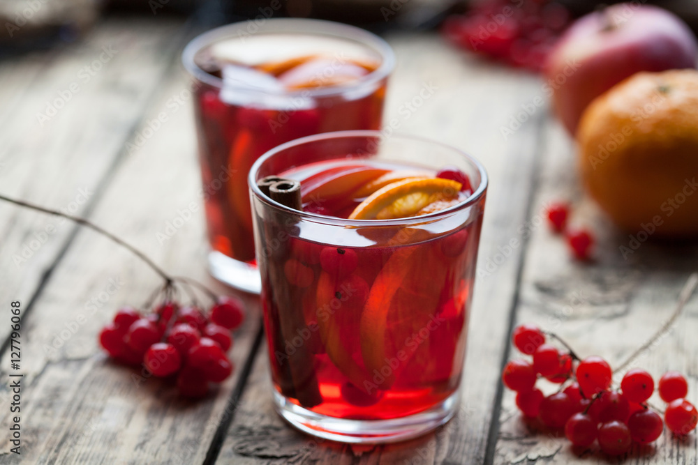 Hot mulled wine or sangria with spices, orange and berries on an old wooden background, selective focus. Berries decoration. Hot mulled wine or sangria with spices, orange and berries on an old wooden background, selective focus. Berries decoration.