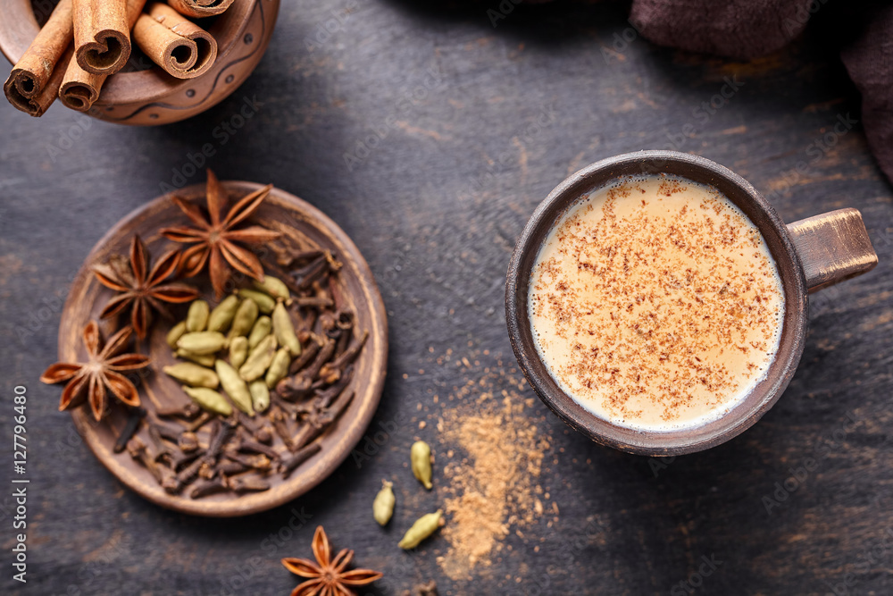 Masala tea chai latte traditional hot Indian sweet milk spiced drink, nutmeg, ginger, cinammon sticks, fresh spices blend, cardamom, anise organic infusion healthy wellness beverage in rustic clay cup