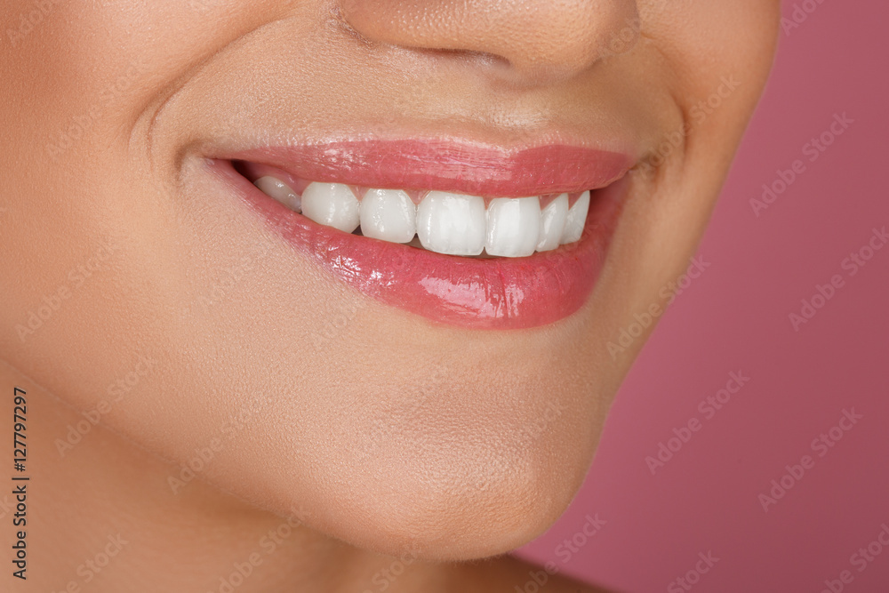 Obraz premium Beautiful smile with whitening teeth. Dental photo. Macro closeup of perfect female mouth, lipscare. Perfect pink lip makeup. Perfect clean skin, light fresh lip make-up. Pink background