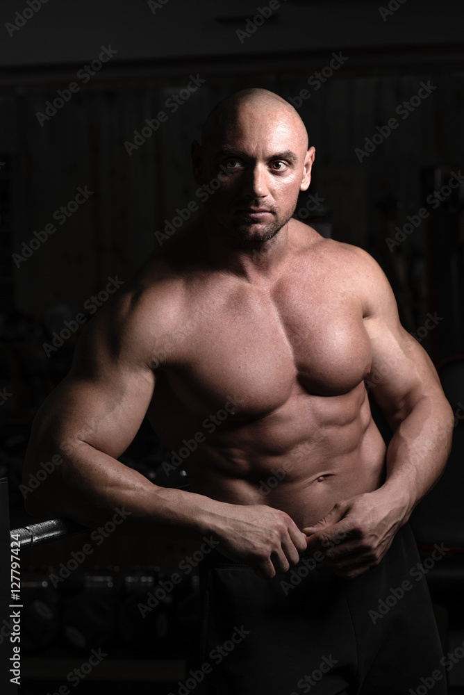 Attractive muscular bodybuilder guy prepare to do exercises with barbell in a gym. Guy bodybuilder tired in gym. Young Man Bodybuilder Resting In Gym After Exercising Attractive muscular bodybuilder guy prepare to do exercises with barbell in a gym. Guy bodybuilder tired in gym. Young Man Bodybuilder Resting In Gym After Exercising