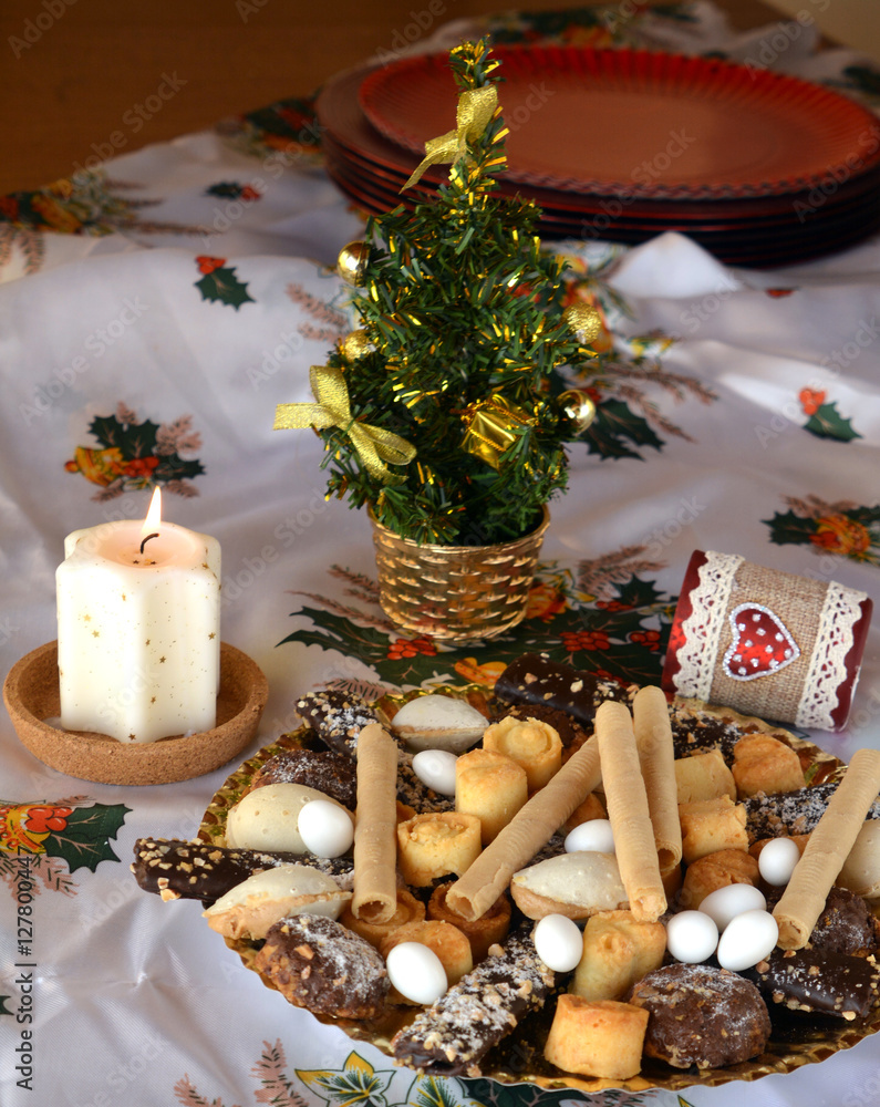Christmas cookies with chocolate,nuts and coconut decorated on a table with lighted candles