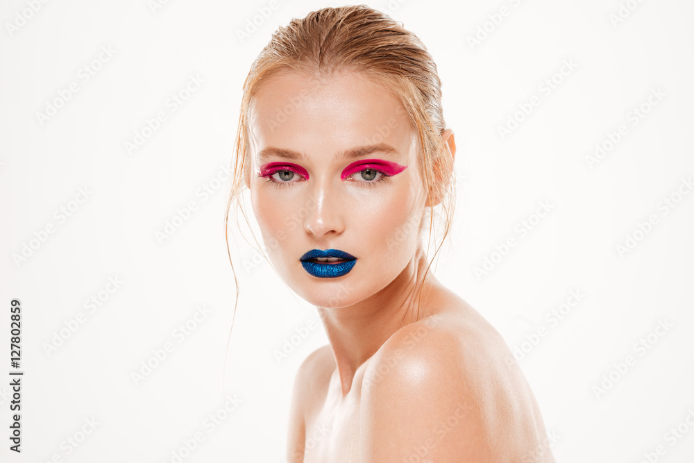 Naked woman stands sideways and looking at the camera