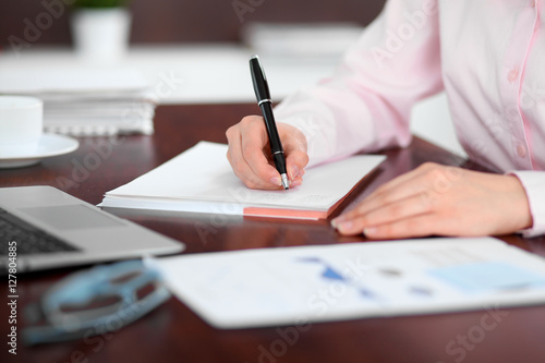 Closeup of a business woman writing in a notebook