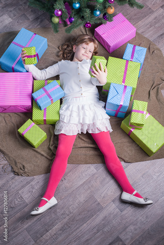 Girl lying on the floor among Christmas gifts