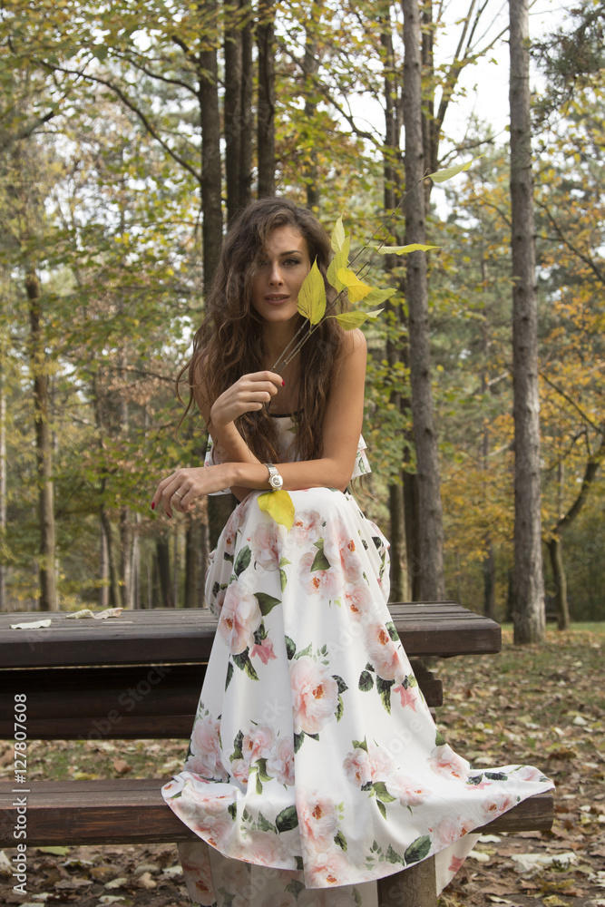 Beautiful girl in dress sitting in the wood