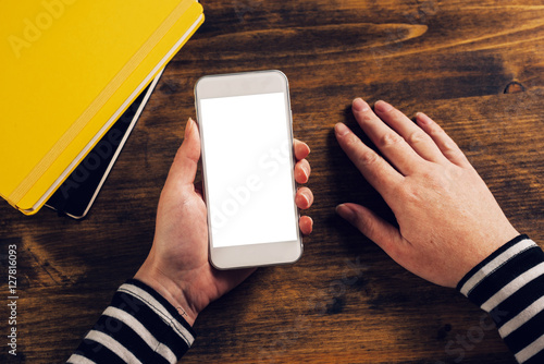 Female hands holding mobile smarthone with blank screen photo