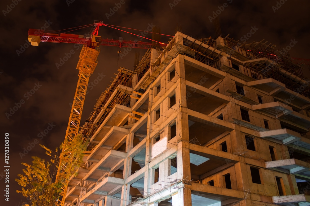 unfinished building and hoisting crane at night time unfinished building and hoisting crane at night time