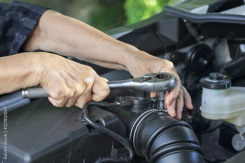 Obraz premium Elderly woman repairing her car