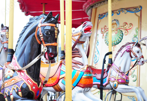 Beautiful horse carousel in a holiday park. Three horses on a traditional fairground vintage carousel. Merry-go-round with horses.