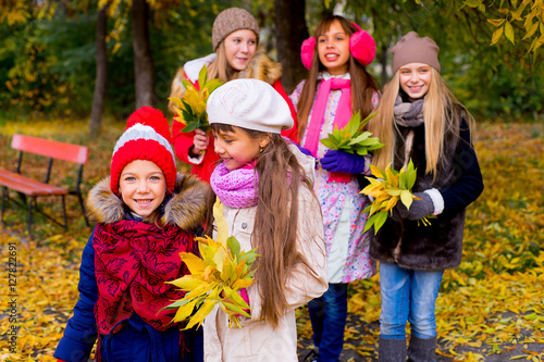 group of girls in autumn park with leafs