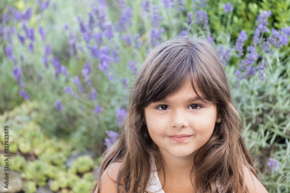 Portrait of cool brunette little girl with violet lavender flower in the background. 