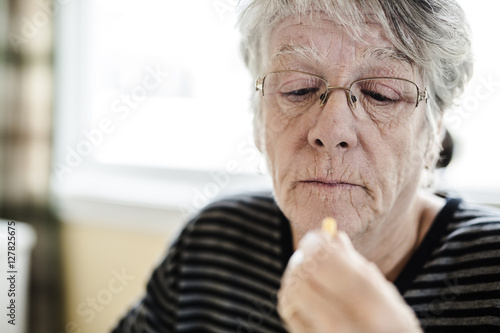 Sick senior woman taking her pills at home