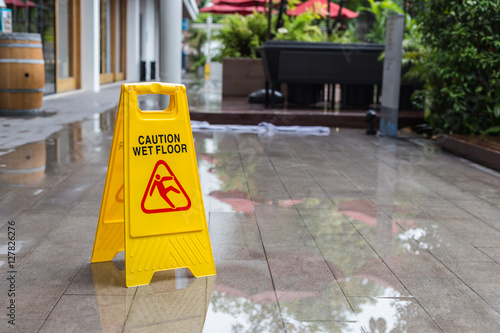 Yellow wet floor warning sign on the floor in hotel photo