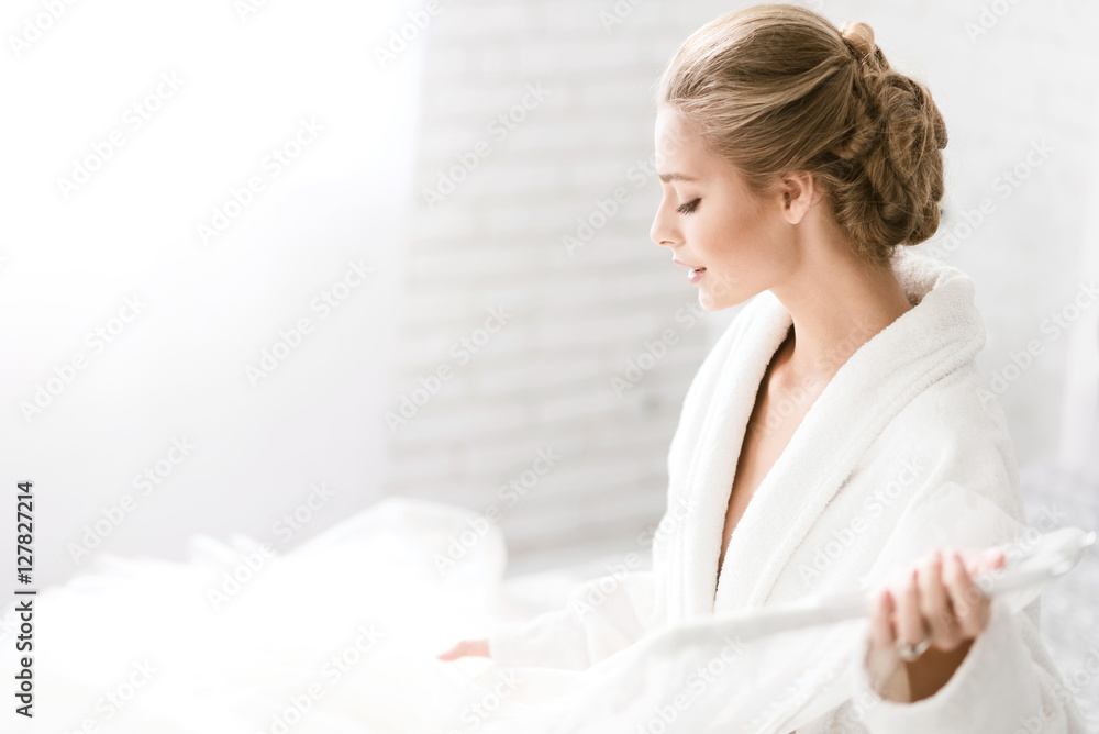 Charming young bride holding her wedding dress Charming young bride holding her wedding dress