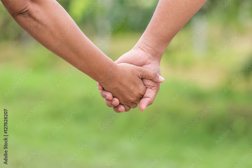 Two hands holding together. Help or support concept. On green bl Two hands holding together. Help or support concept. On green bl