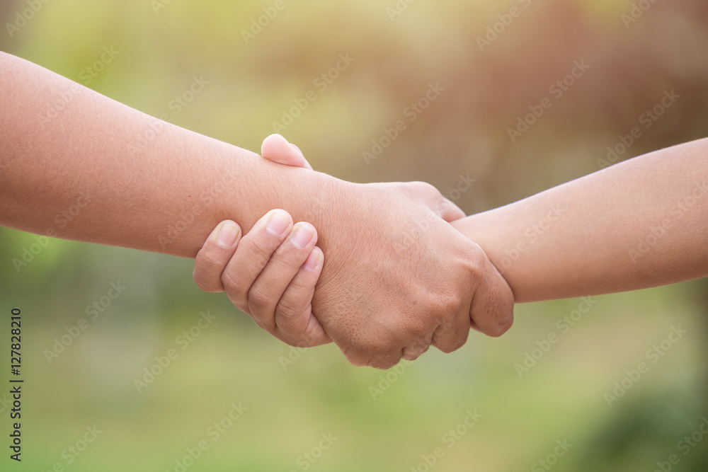 Two hands holding together. Help or support concept. On green bl Two hands holding together. Help or support concept. On green bl