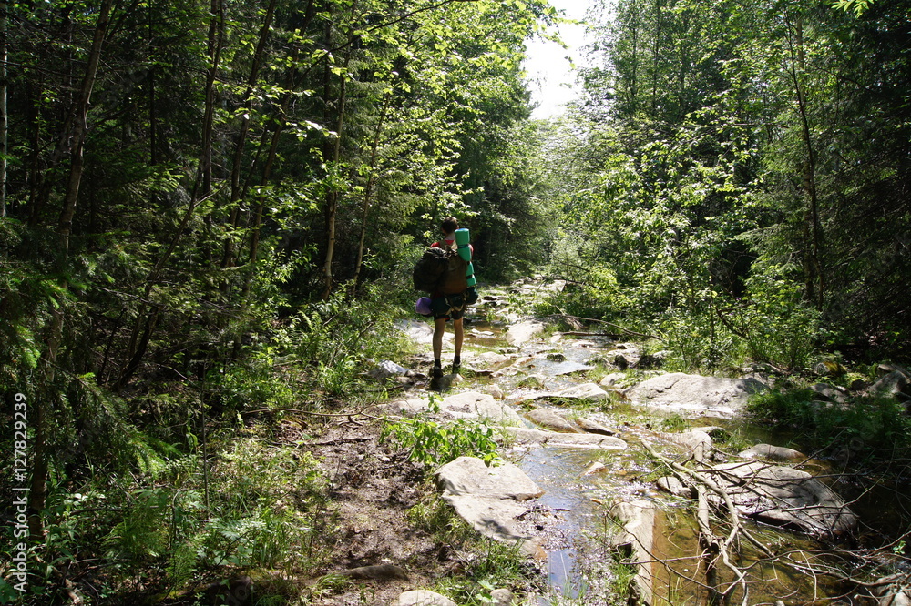 backpacker goes on stream in the mountains backpacker goes on stream in the mountains